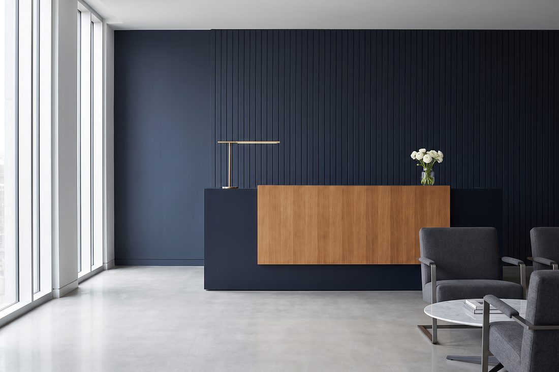 The calm reception area of a tax office, with a navy desk, brass lamp and soft daylight.