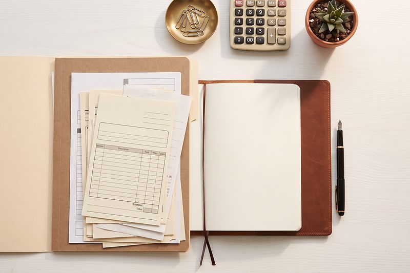 Tax documents, a notebook and a calculator arranged neatly on a desk.
